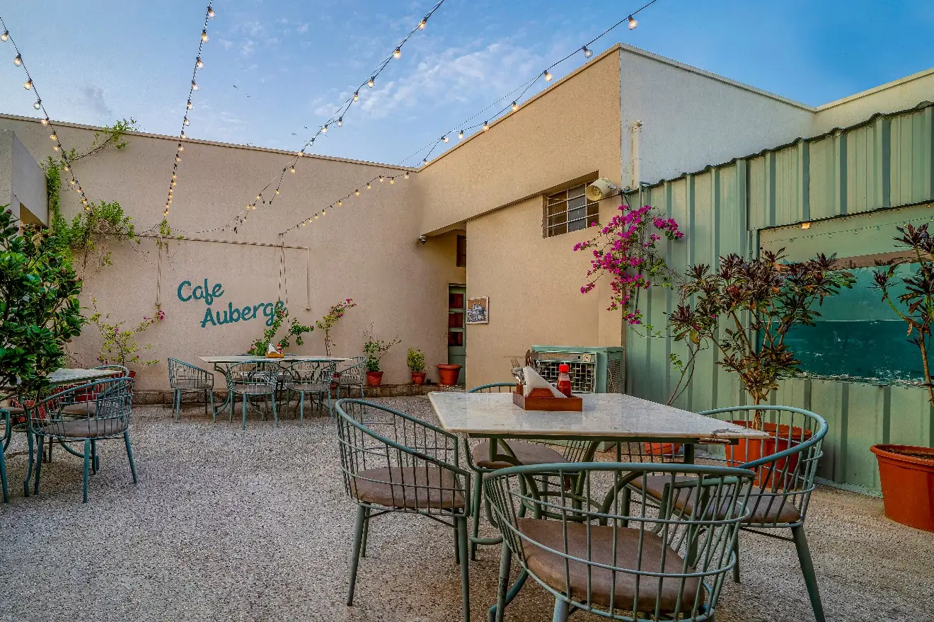The open-air courtyard at Café Auberge, Civil Lines, Jaipur, with string lights and the café's name painted on the wall