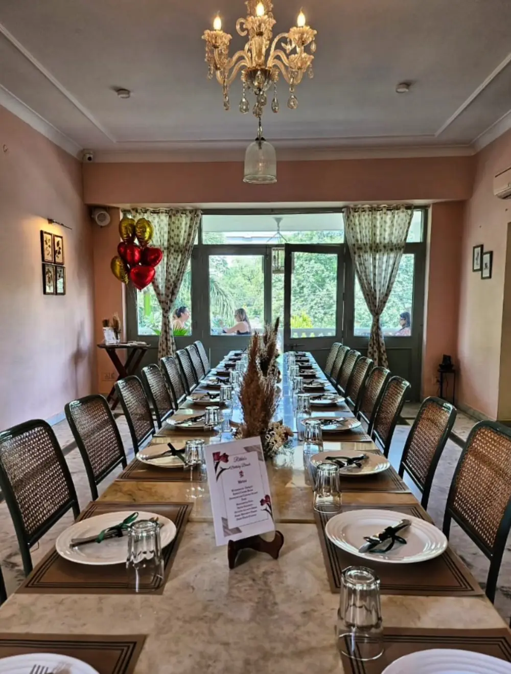 A long table set for a group dinner under a chandelier